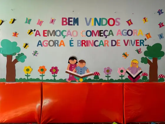 Painel de boas-vindas e o banco almofadado que protege a parede